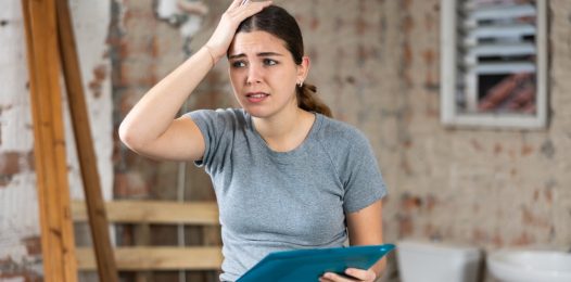 Disappointed young woman architect standing in building site, frustrated by documentation mistake.